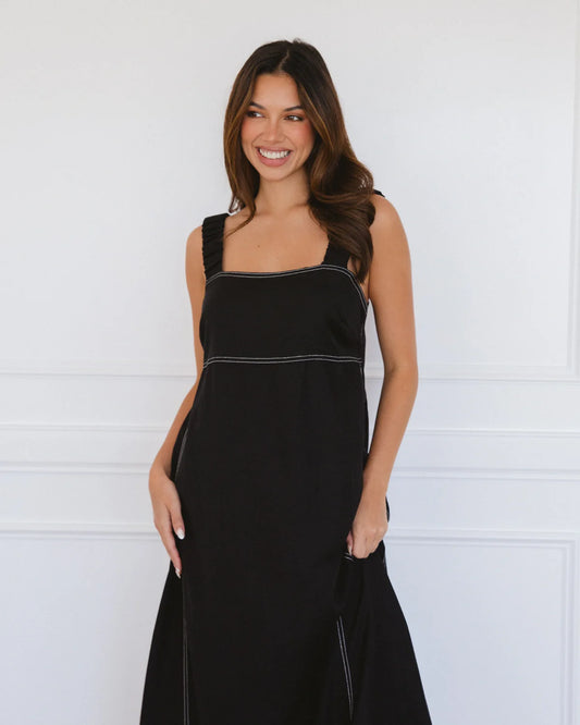 Woman wearing a black dress with white trim against a white background