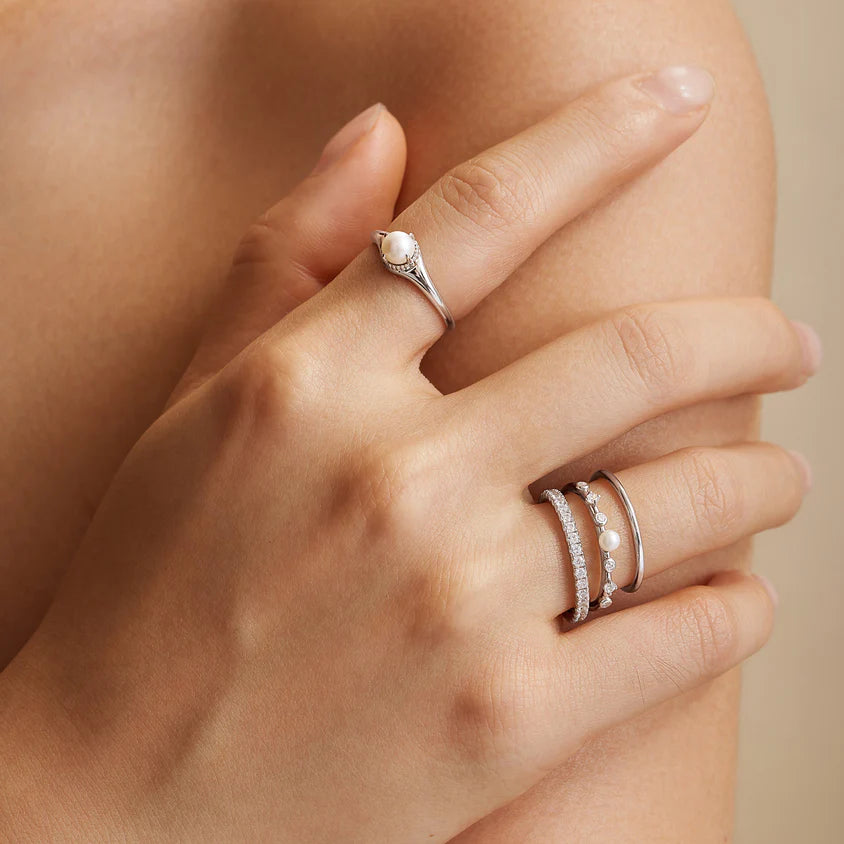 Close-up of a hand wearing two silver rings on a neutral background