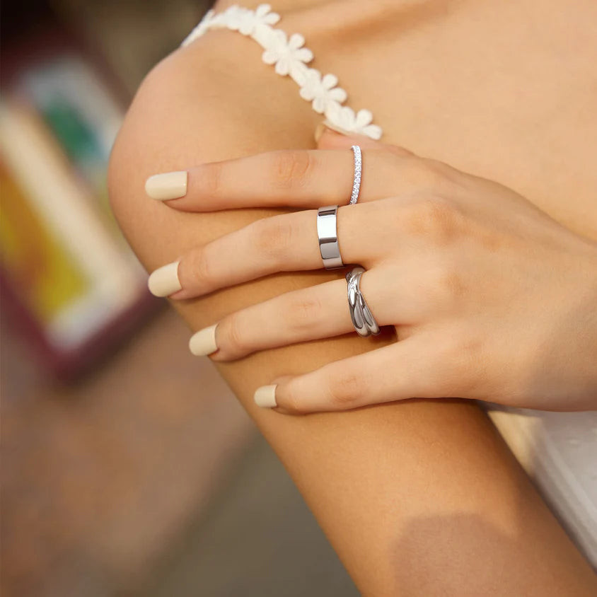 Close-up of a hand wearing two silver rings with a blurred background